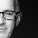 Black-and-white close-up of a man wearing glasses.